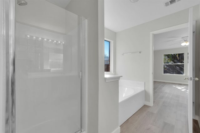 bathroom with plus walk in shower, wood-type flooring, and ceiling fan