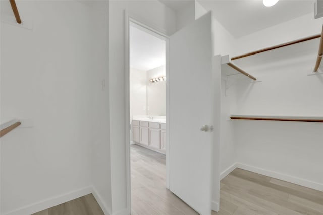 spacious closet featuring sink and light hardwood / wood-style flooring