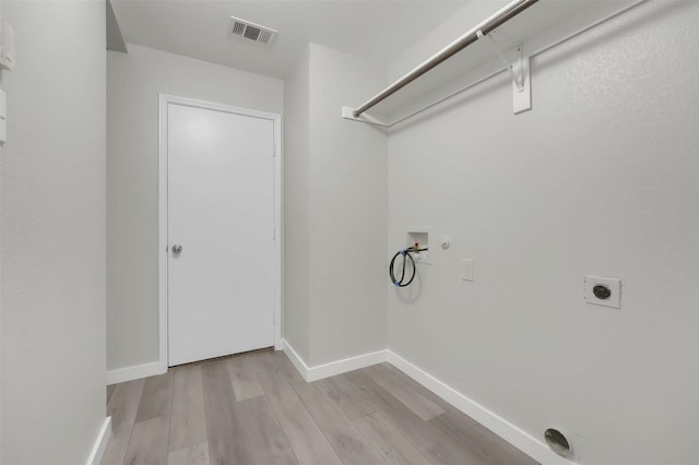 clothes washing area featuring hookup for an electric dryer, hookup for a washing machine, and light hardwood / wood-style flooring