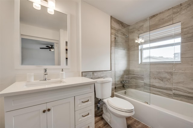 full bathroom with vanity, ceiling fan, wood-type flooring, enclosed tub / shower combo, and toilet