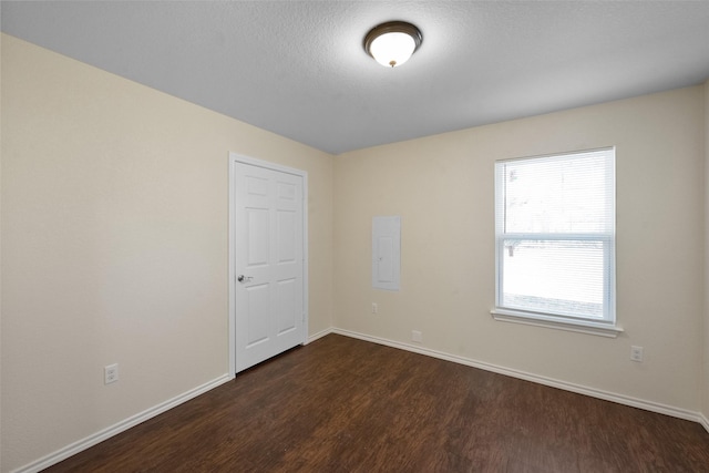 spare room featuring dark hardwood / wood-style flooring and electric panel