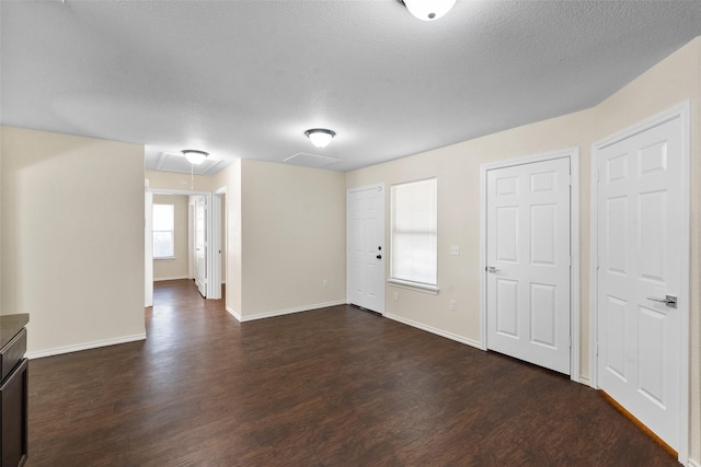 empty room with a healthy amount of sunlight, dark hardwood / wood-style flooring, and a textured ceiling