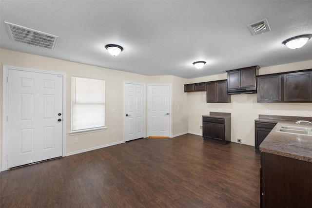 kitchen with a textured ceiling, dark brown cabinets, sink, and dark hardwood / wood-style floors