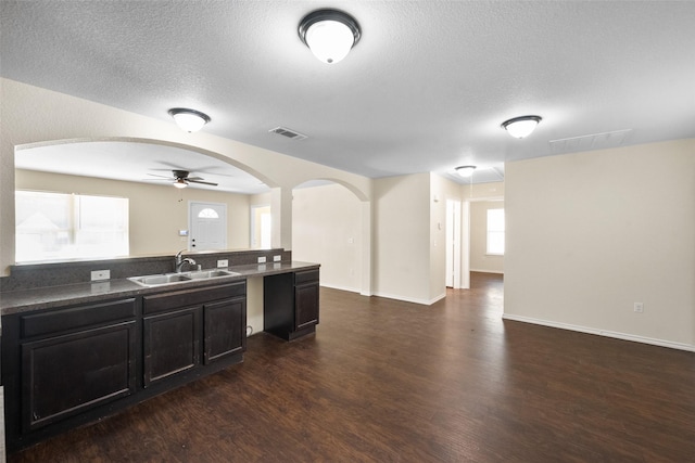 kitchen featuring a textured ceiling, ceiling fan, sink, and dark wood-type flooring