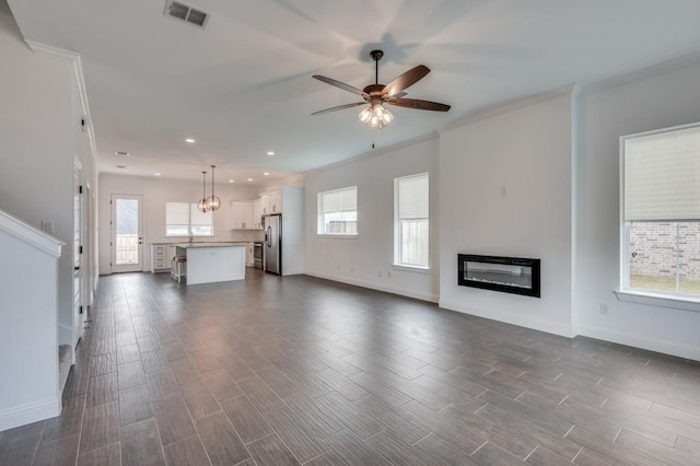 unfurnished living room featuring plenty of natural light, crown molding, and ceiling fan