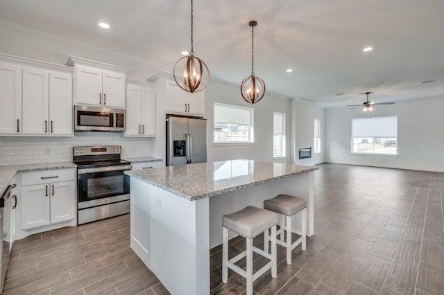 kitchen with white cabinetry, a center island, ceiling fan with notable chandelier, and appliances with stainless steel finishes