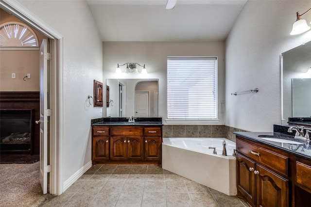 bathroom featuring tile patterned floors, vanity, lofted ceiling, and a tub to relax in