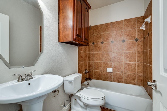 full bathroom with sink, tiled shower / bath combo, and toilet