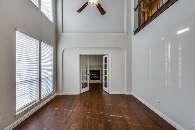 unfurnished living room with a wealth of natural light, french doors, dark hardwood / wood-style flooring, and ceiling fan