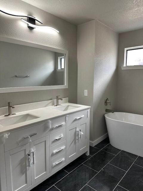 bathroom with a bathing tub, vanity, and a textured ceiling