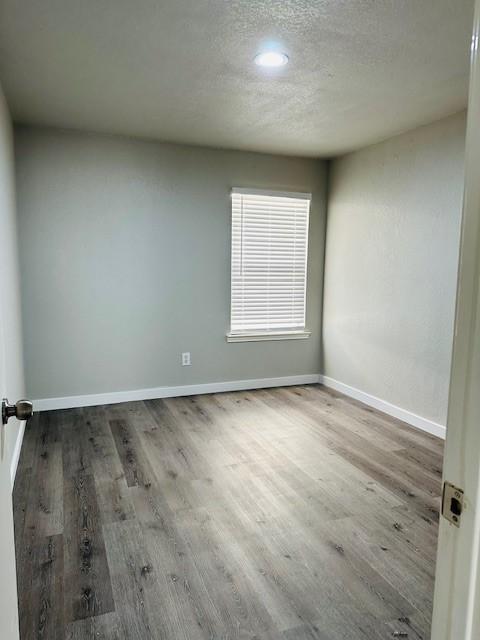 unfurnished room with hardwood / wood-style flooring and a textured ceiling