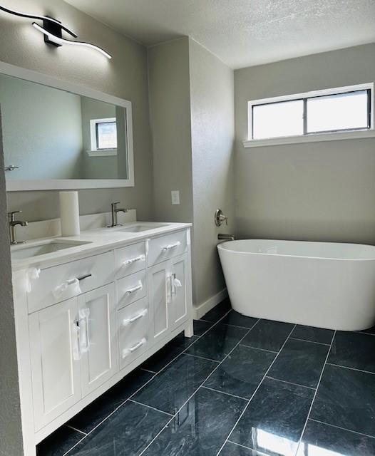 bathroom with a washtub, a textured ceiling, and vanity