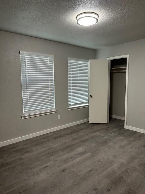 unfurnished bedroom featuring dark hardwood / wood-style floors, a textured ceiling, and a closet