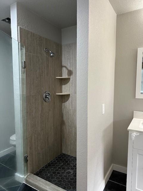 bathroom with tile patterned floors, vanity, an enclosed shower, and toilet