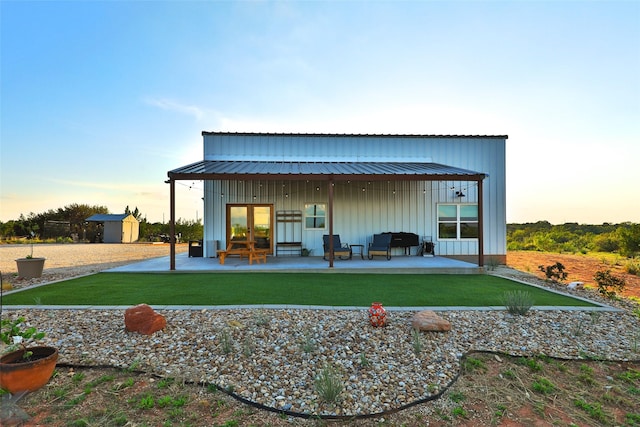 back house at dusk featuring a storage unit and a patio