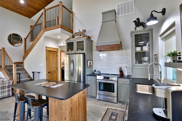 kitchen with appliances with stainless steel finishes, backsplash, gray cabinets, and custom range hood