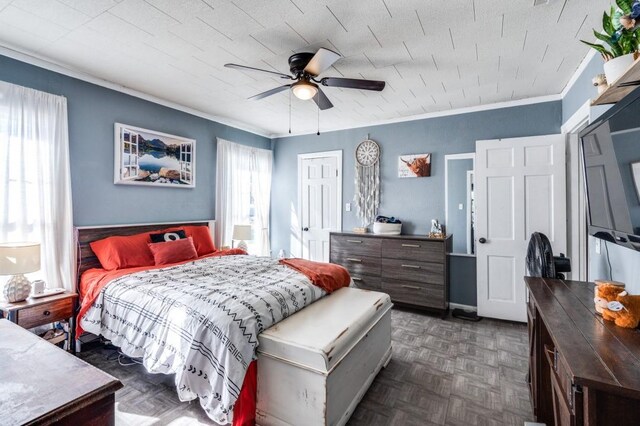 bedroom with dark parquet flooring, ceiling fan, a closet, and ornamental molding