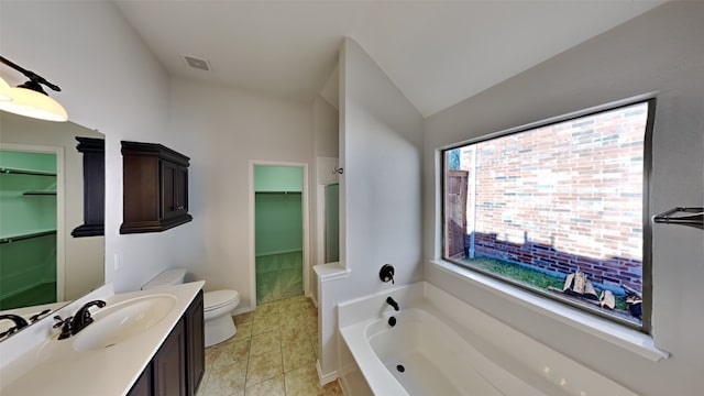 bathroom featuring vanity, a bath, vaulted ceiling, tile patterned flooring, and toilet