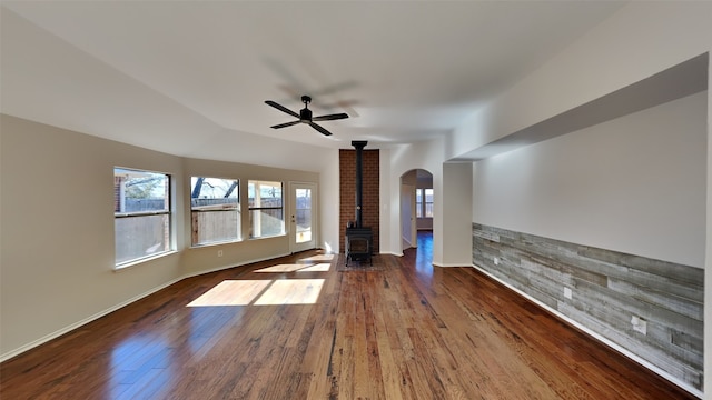 unfurnished living room featuring a wood stove, ceiling fan, and hardwood / wood-style flooring