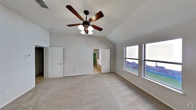 carpeted spare room with ceiling fan and vaulted ceiling