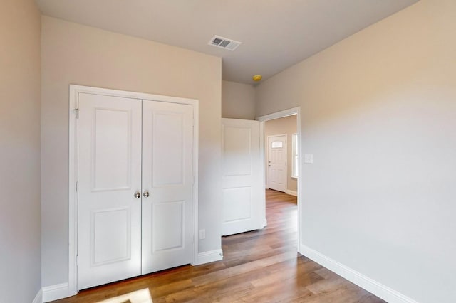 unfurnished bedroom with light wood-type flooring and a closet