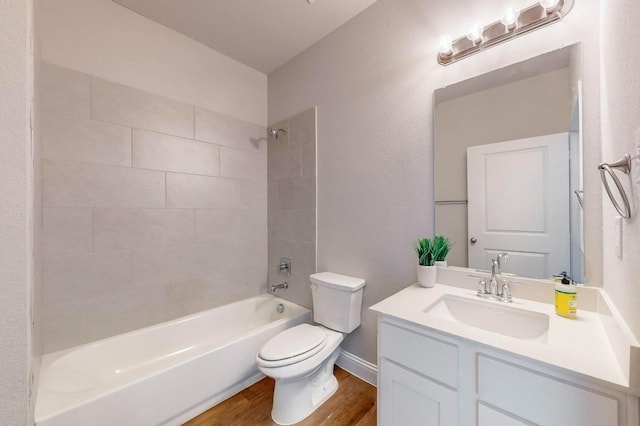 full bathroom featuring vanity, hardwood / wood-style floors, tiled shower / bath, and toilet