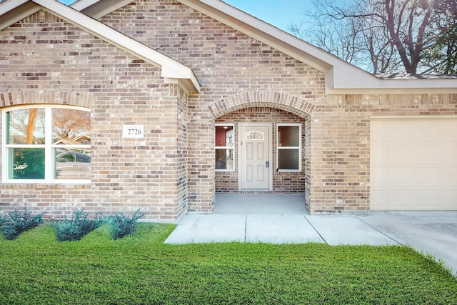 entrance to property featuring a lawn and a garage