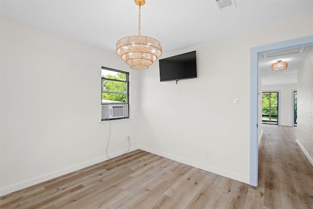 unfurnished room with a chandelier, light hardwood / wood-style flooring, a healthy amount of sunlight, and a textured ceiling