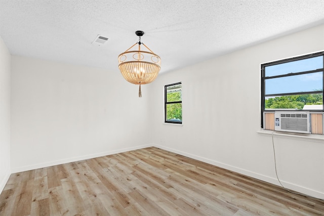 spare room with a textured ceiling, light hardwood / wood-style flooring, and cooling unit