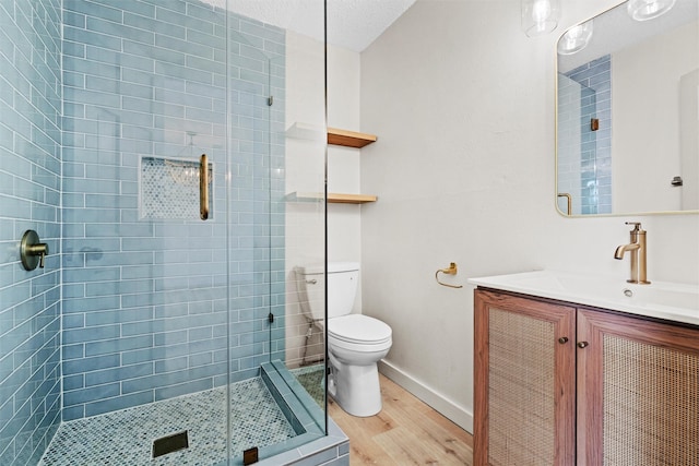 bathroom with vanity, a shower with door, hardwood / wood-style flooring, toilet, and a textured ceiling