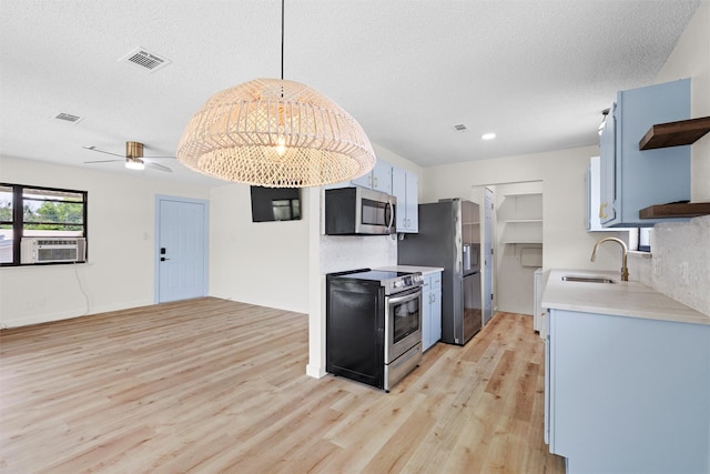 kitchen with sink, hanging light fixtures, ceiling fan, light hardwood / wood-style floors, and stainless steel appliances