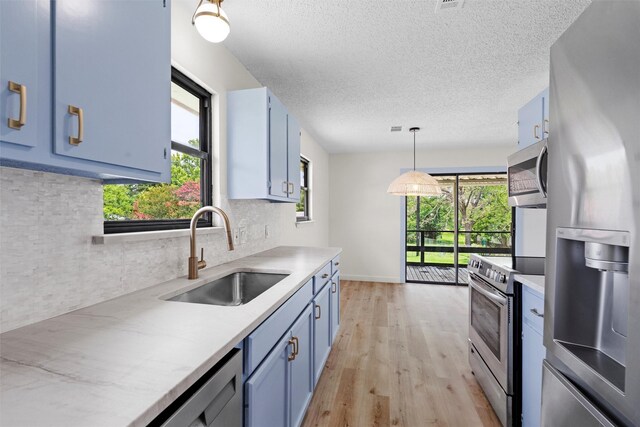 kitchen with pendant lighting, blue cabinetry, sink, and appliances with stainless steel finishes