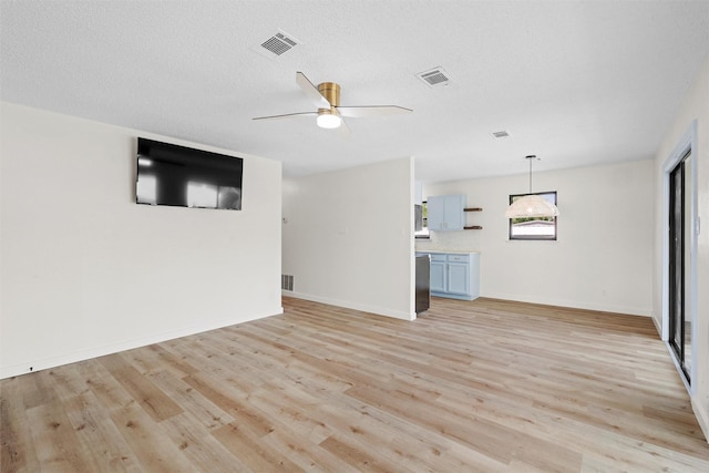 unfurnished living room with ceiling fan, a textured ceiling, and light wood-type flooring