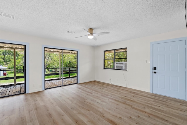 unfurnished room featuring ceiling fan, cooling unit, light wood-type flooring, and a textured ceiling