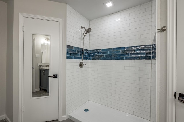 bathroom with a tile shower and vanity