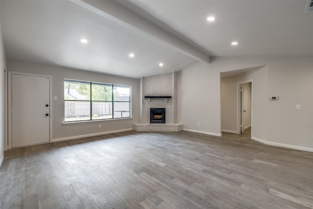 unfurnished living room with a fireplace, lofted ceiling with beams, and light hardwood / wood-style flooring