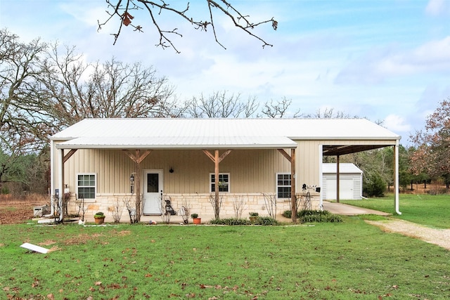 view of front of house featuring a garage, an outbuilding, and a front lawn