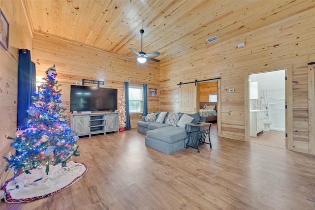 living room featuring a barn door, wooden walls, wood ceiling, and wood-type flooring