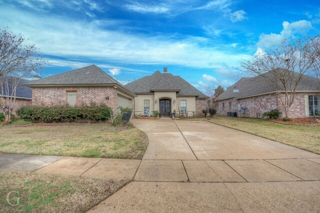 french country home with cooling unit, a garage, and a front yard