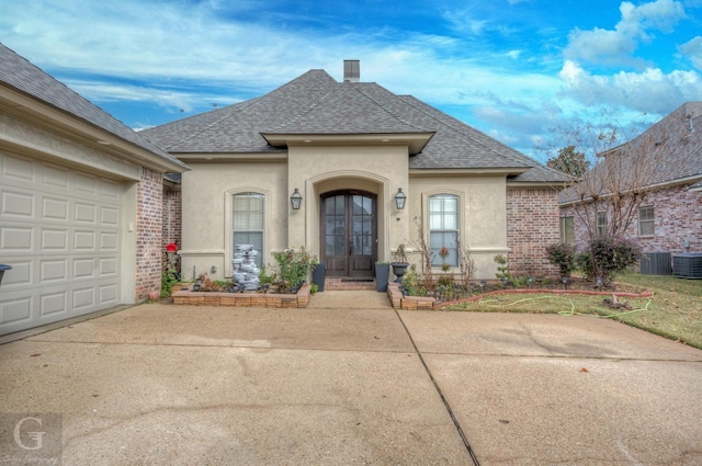 view of front of property with cooling unit, a garage, and french doors