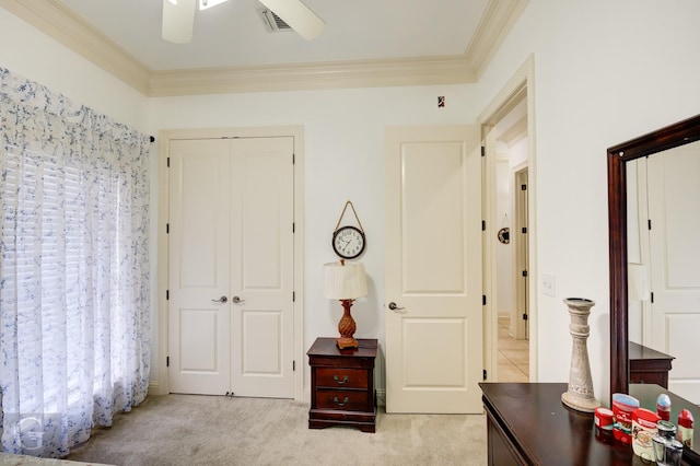 carpeted bedroom with ceiling fan, ornamental molding, and a closet