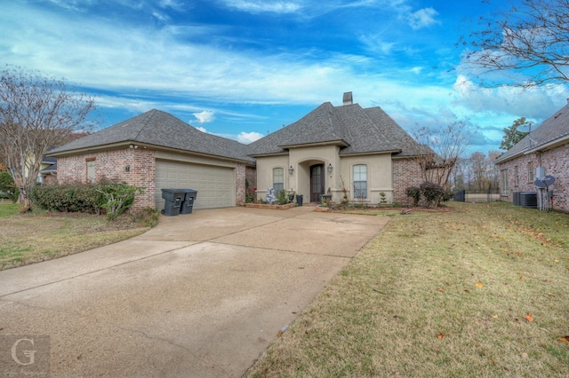 french country style house with a garage and a front lawn