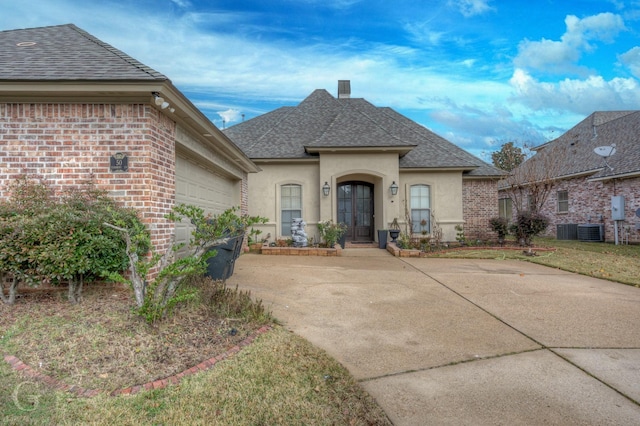 view of front of house with french doors, cooling unit, and a garage