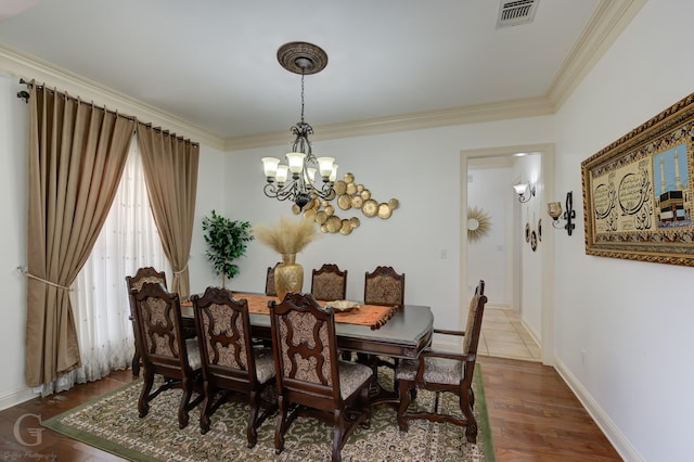 dining area featuring wood-type flooring, ornamental molding, and an inviting chandelier