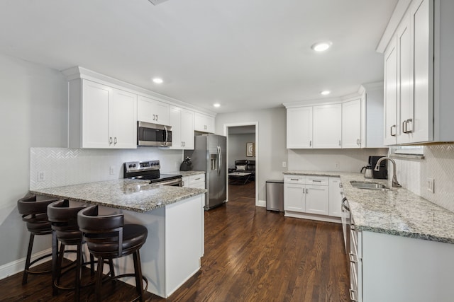 kitchen featuring appliances with stainless steel finishes, light stone countertops, sink, and white cabinets