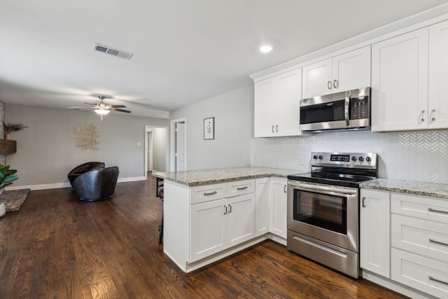 kitchen with light stone counters, appliances with stainless steel finishes, kitchen peninsula, and white cabinets