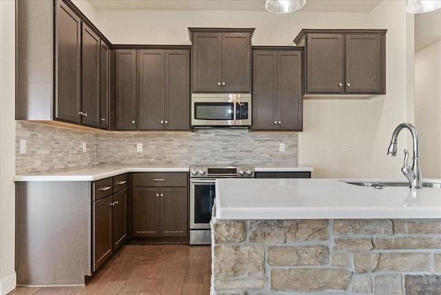 kitchen with appliances with stainless steel finishes, dark hardwood / wood-style flooring, dark brown cabinetry, and sink