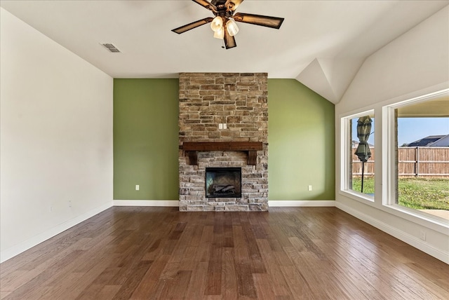 unfurnished living room with ceiling fan, lofted ceiling, dark hardwood / wood-style floors, and a stone fireplace