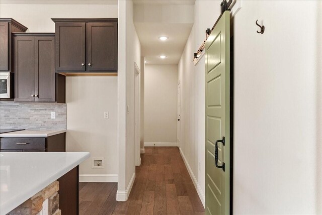 hallway featuring a barn door and dark hardwood / wood-style flooring