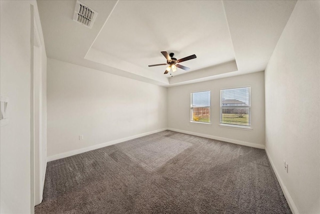 carpeted spare room with ceiling fan and a tray ceiling